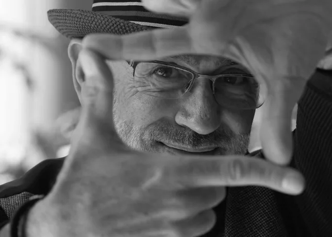 Daniel Cubillo, author of The Creative Masterind mind, peeks through his hands, resembling a television frame.