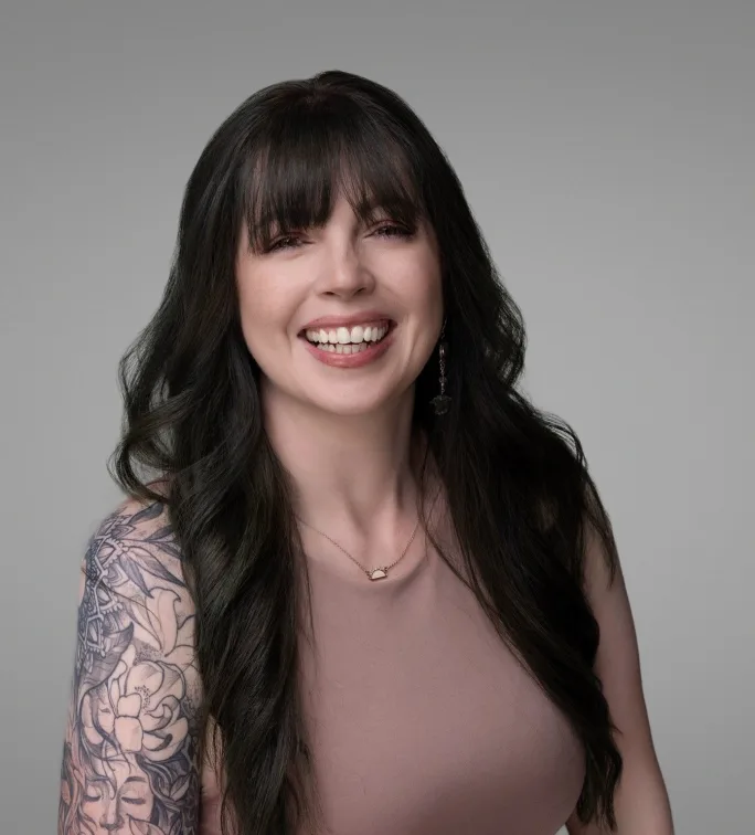 Jacquelyn Rodriguez in a taupe tank top that shows off a sleeve of tattoos.