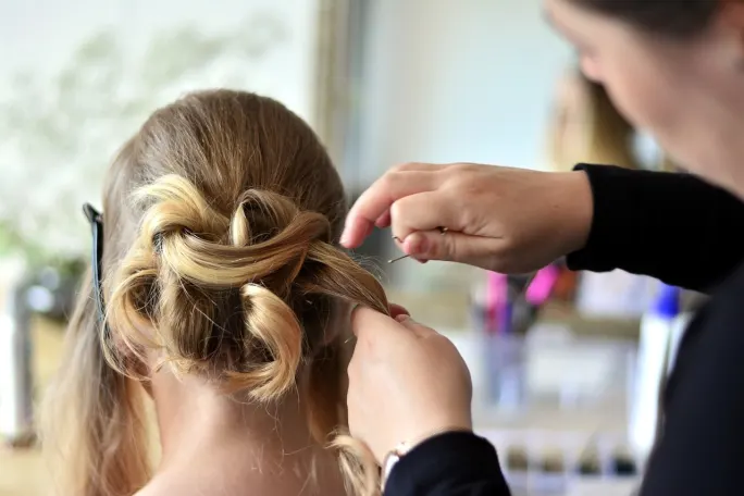 A hairstylist creating an upstyle on a client