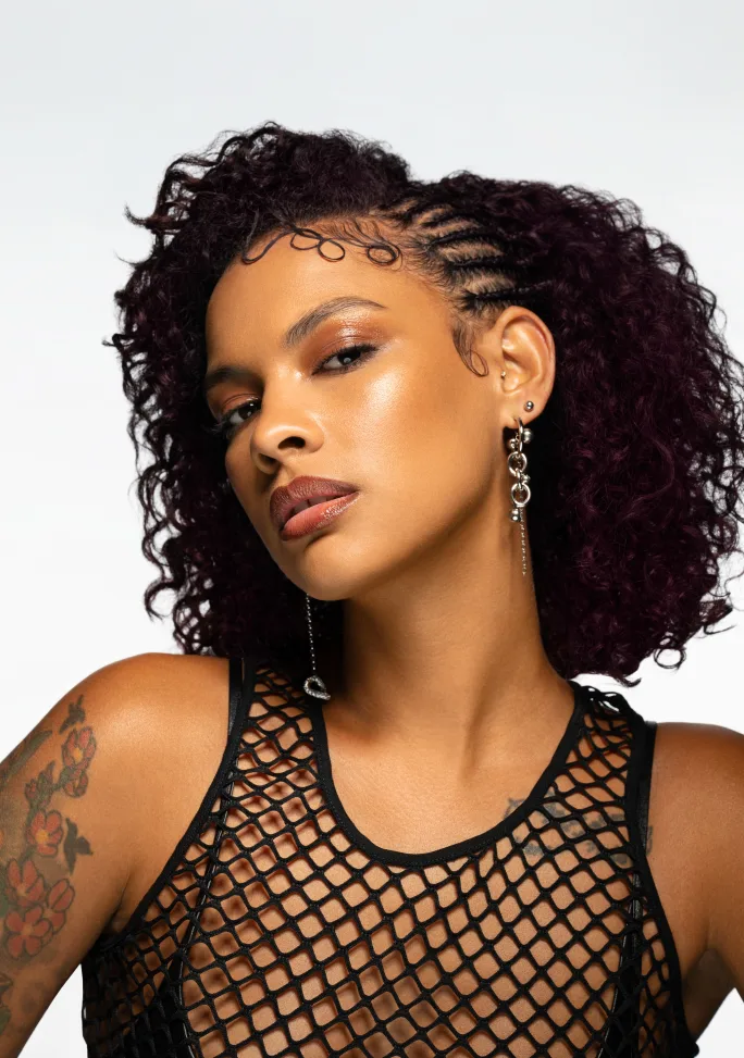 A model with brunette hair and a red wash, with small braids.