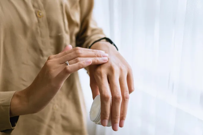 A woman rubs a cream into her hand