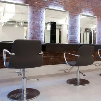 A row of salon chairs in front of columns and mirrors at JBW Jeffrey Ching Salon
