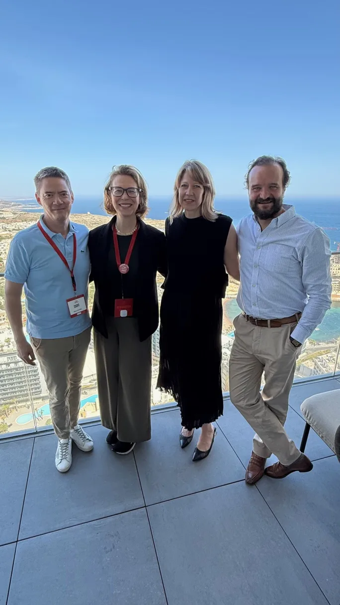 Four people smile on a hotel balcony