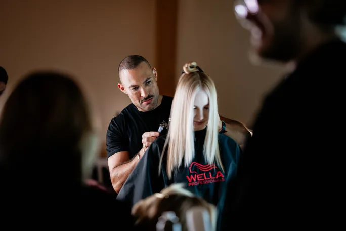 A stylist works on a model's hair.
