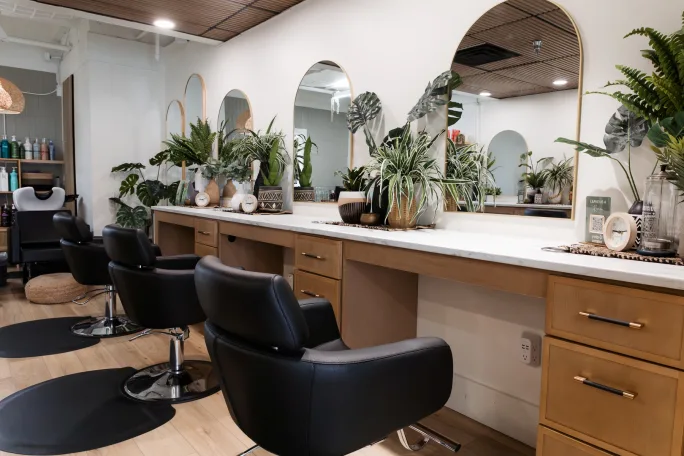 A row of salon chairs in front of mirrors at M. Hair Studio.