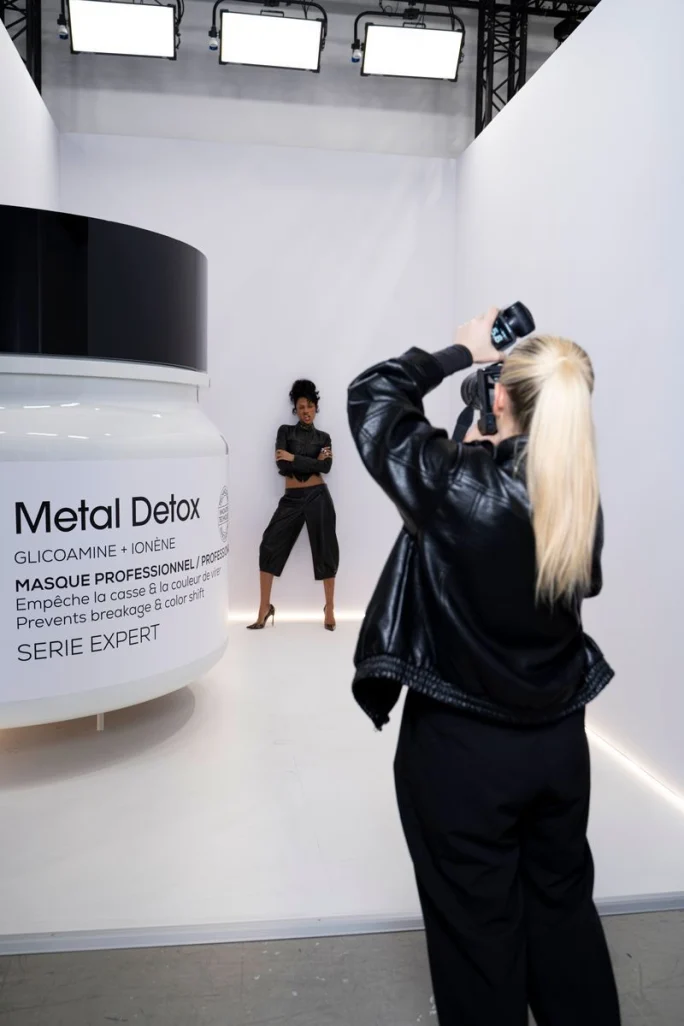 A photographer holds her camera up as a model strikes a pose at Transformation Day