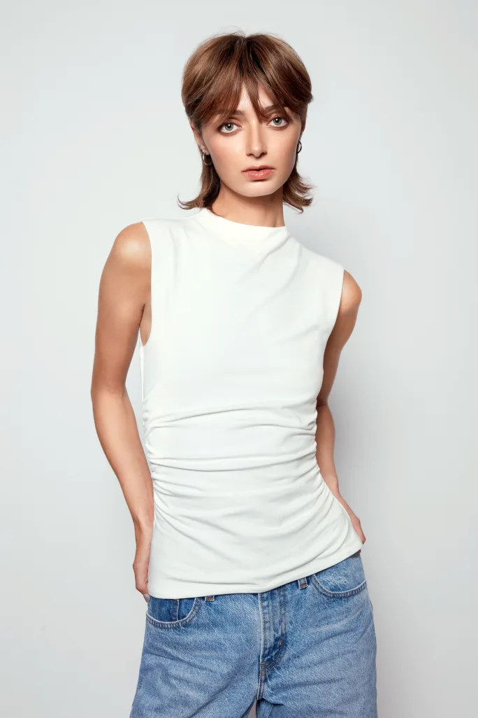 A woman in white tshirt and jeans and light brown hair.