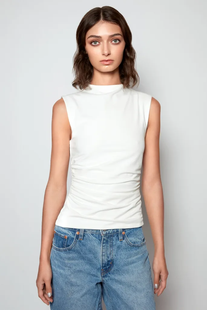 A woman in white t shirt and jeans, and medium brown hair.