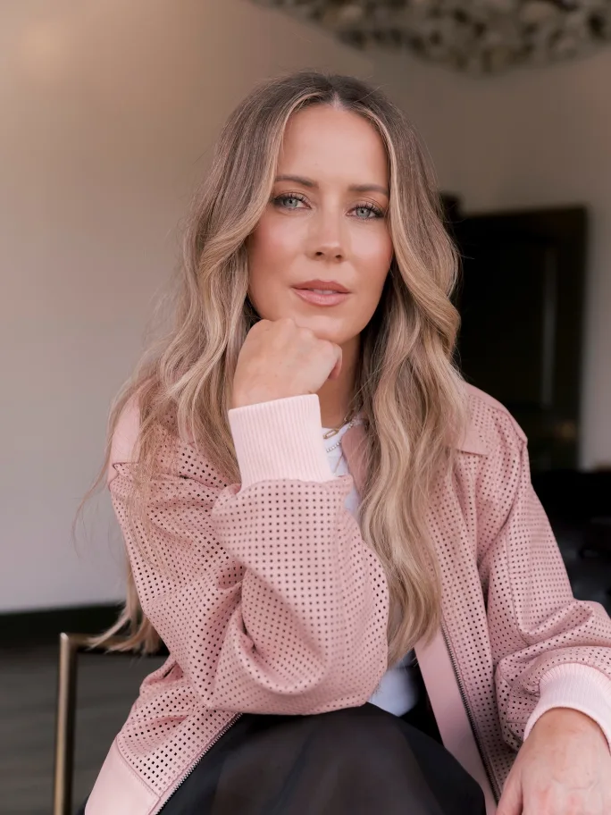 A woman with long hair and her hand under her chin.