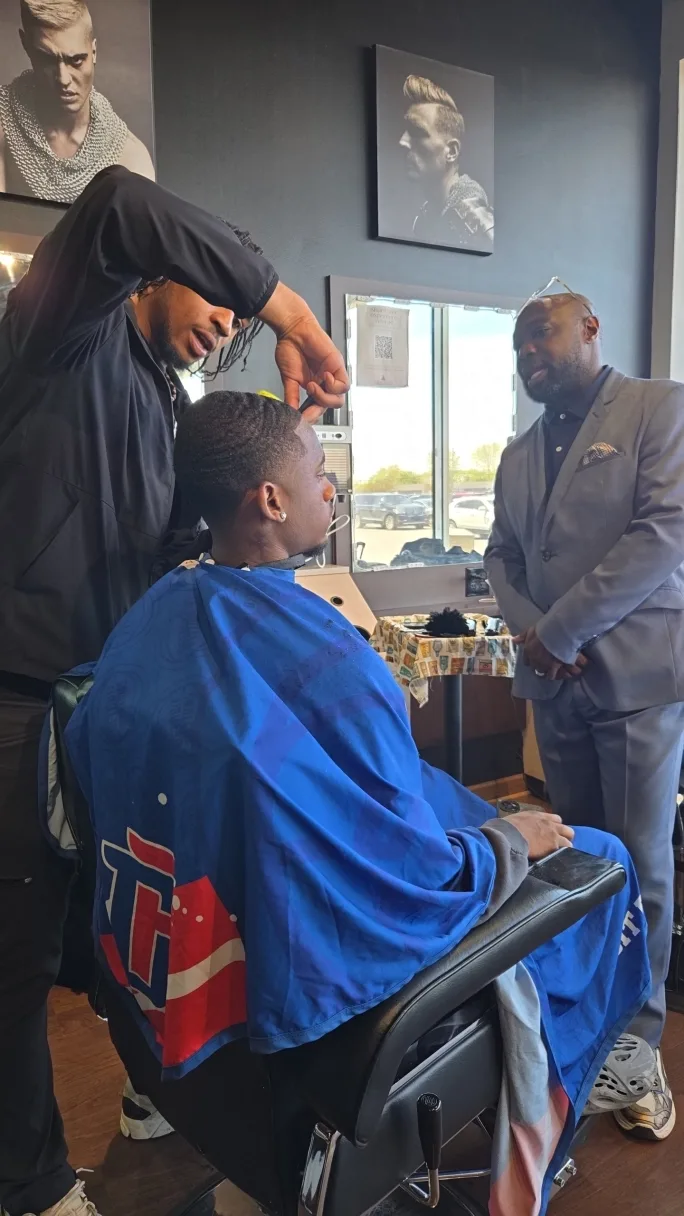 Man instructing a future barber in a professional training environment.