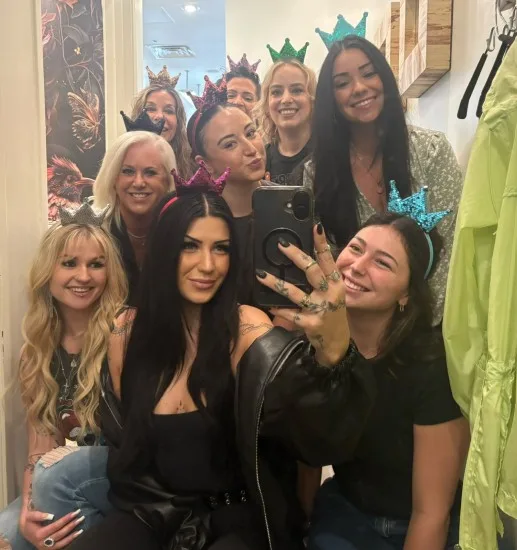 A team of stylists dressed in colorful crowns and taking a selfie.
