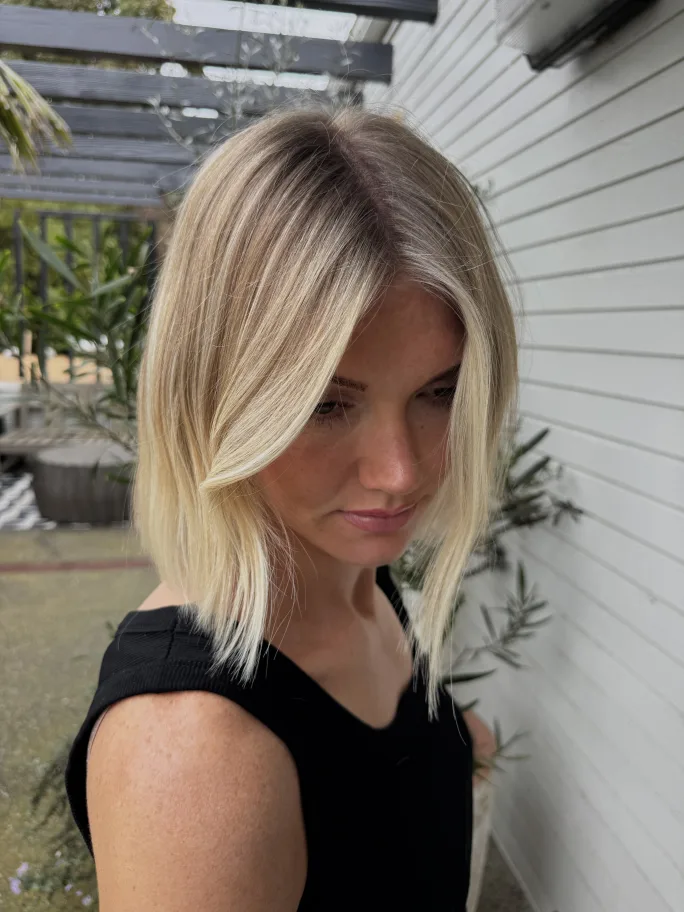 Young woman showcasing long highlighted hair with bright face-framing pieces.