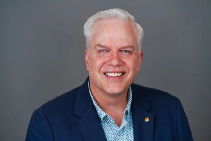 A smiling man with white hair.