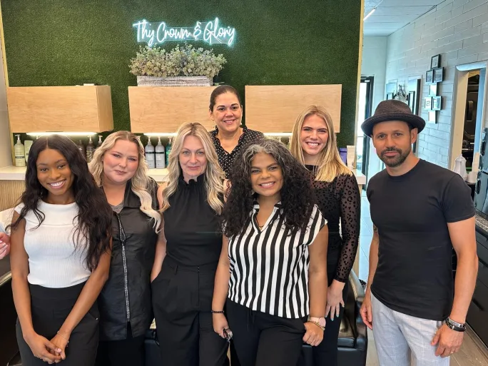 The team from  Thy Crown and Glory Salon & Headspa pose under their logo in neon.