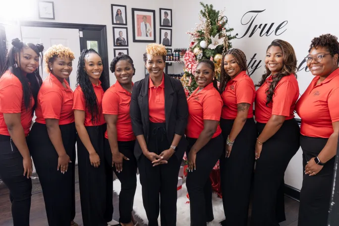 Posing in matching red shirts, the team from True Beauty Salon