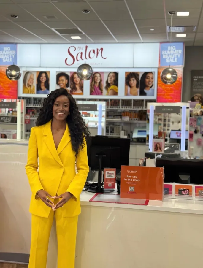 A woman wearing a bright yellow pantsuit stands inside an Ulta store.