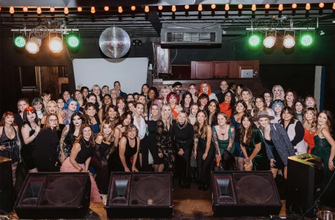 A large group of employees in cocktail attire at an Urban Betty holiday party.