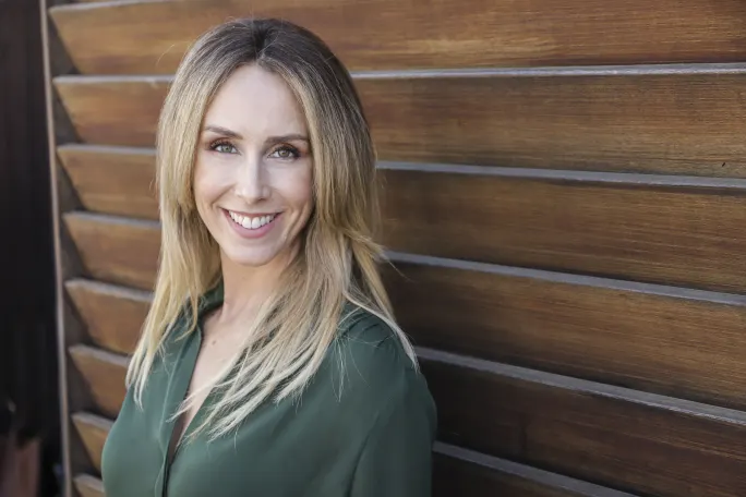 A blonde in green against wood slats.
