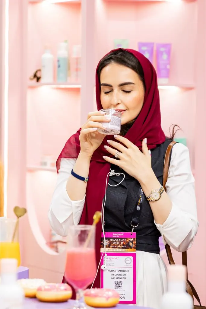Woman holding a fragrance tester strip and smelling perfume at Beautyworld Middle East 2025.
