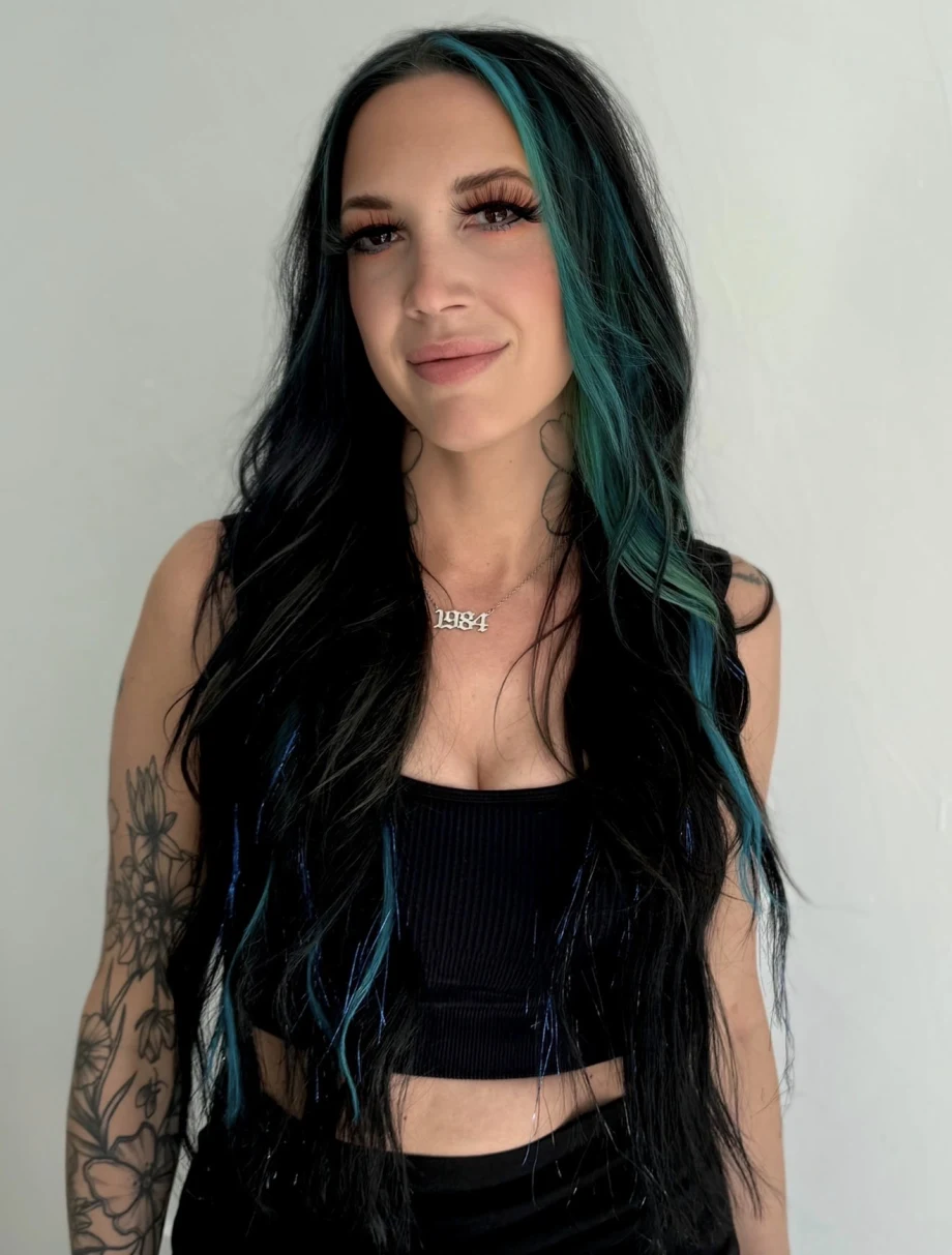 A young woman with long black and green hair, in a black crop top.