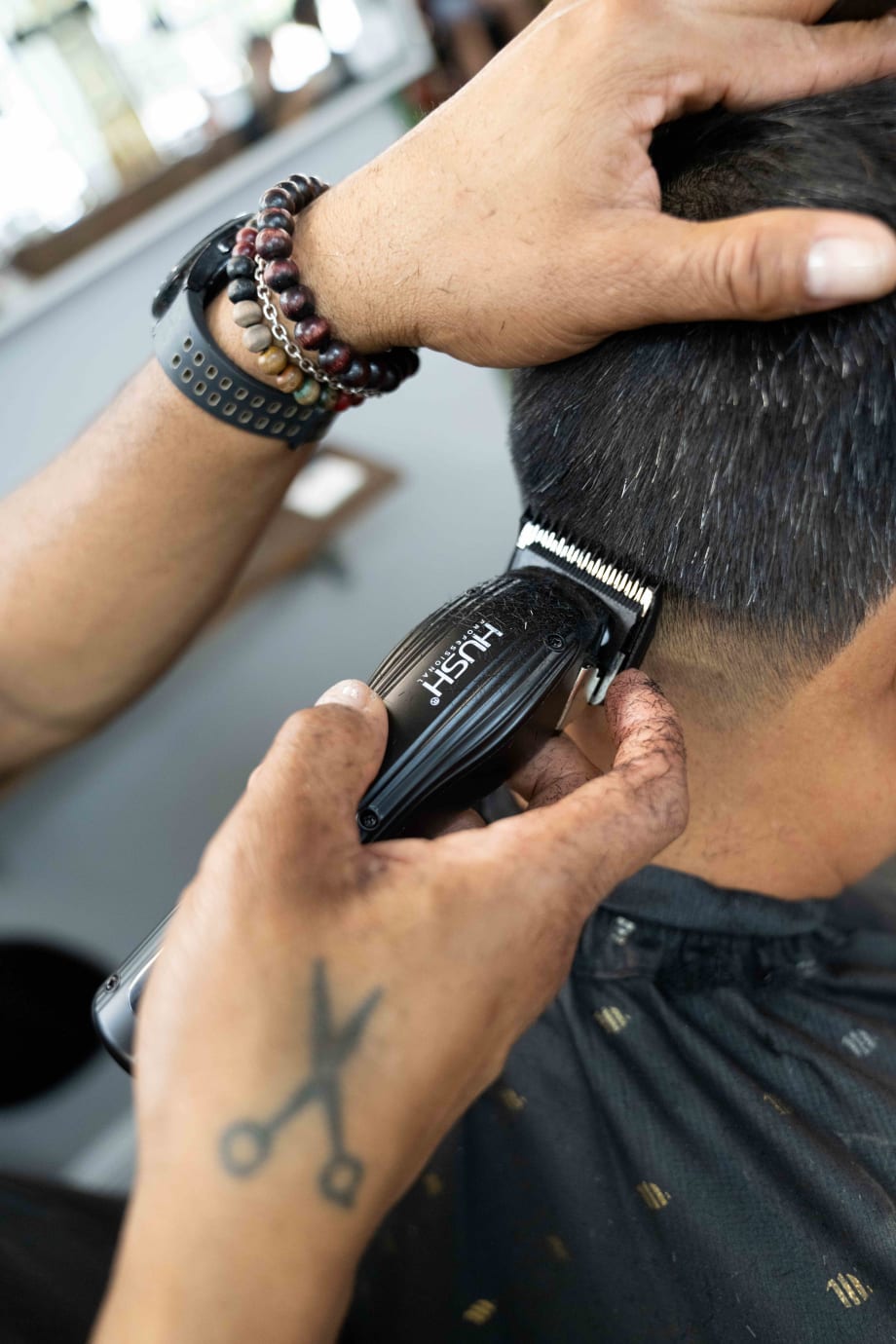 A barber holds a clippers and works on a client's neck
