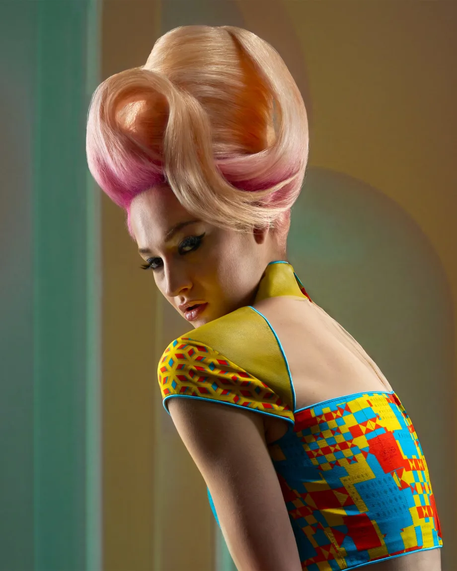 A model with a pink bouffant hairstyle in a multicolored shirt