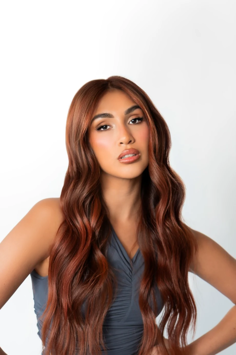 A model with long red hair, arms akimbo.