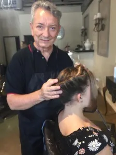 A male hairstylist standing behind a female client who is seated