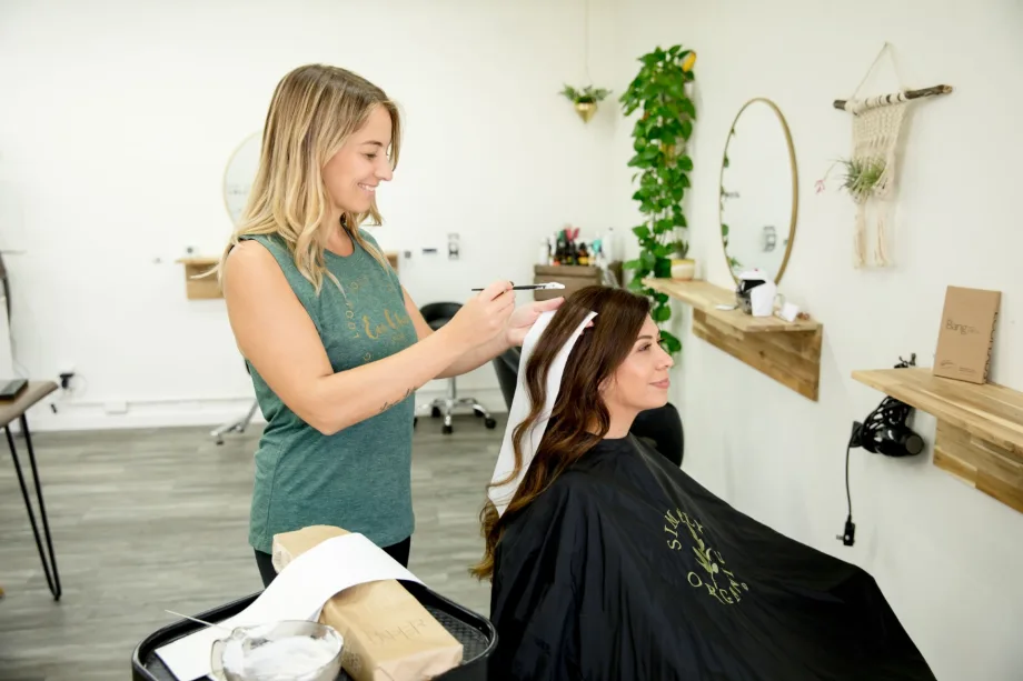 A colorist applies hair color to a client at Eco Salon.