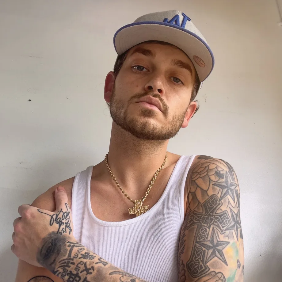 a man with tattoos and a baseball cap