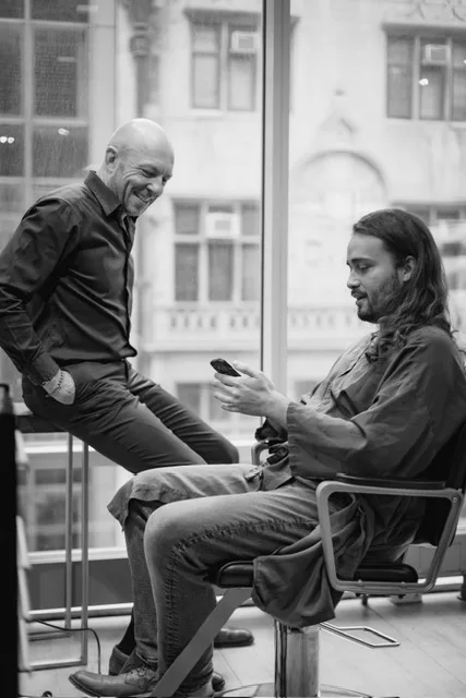 Two men talking and smiling, in profile.