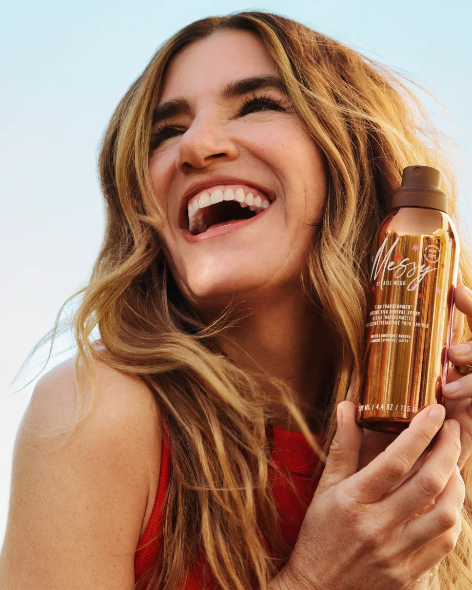 A smiling woman holding a product