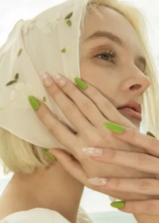 A young woman with blonde hair, a head scarf, and green nails.
