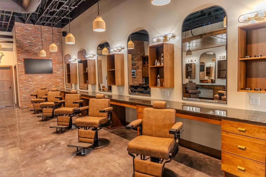 A row of brown barbershop chairs, stations and large arched mirrors at Parlor by Thompson and Company.