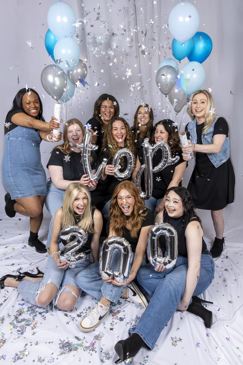 Surrounded by balloons and holding champagne, the excited team from Pure Salon Spa.