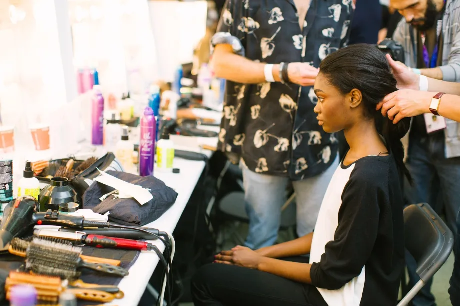 A model has her hair arranged by a hairdresser.