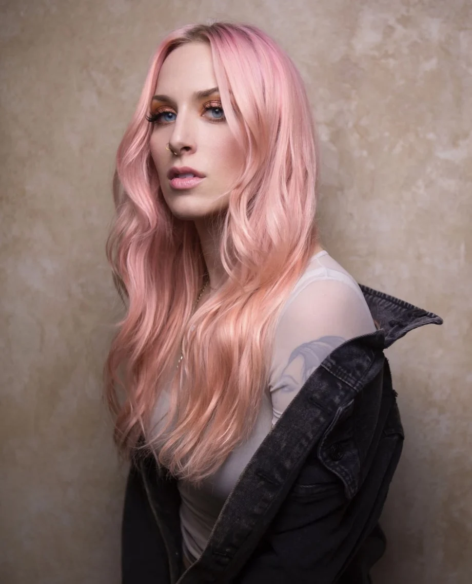 A woman with pink hair and a serious expression.