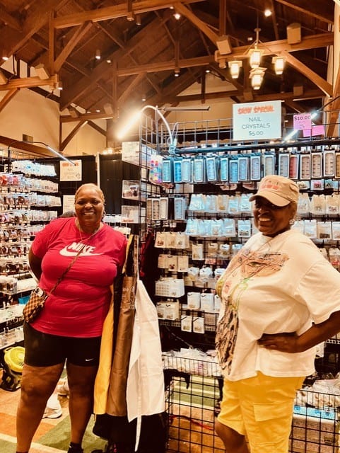 Uniquely Created Bling owner Apryll Cook standing with Sister Simone, both smiling at the event.