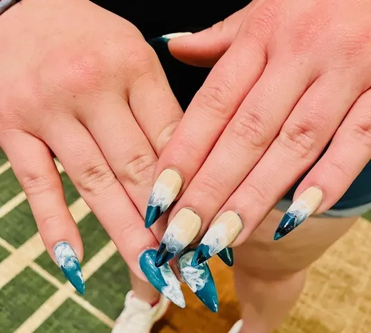 Close-up of a tech’s “Shark Week” nail design featuring underwater-themed art with glow-in-the-dark effects.