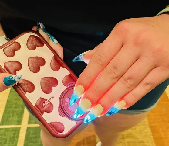 Glow-in-the-dark sharks on the “Shark Week” nails illuminated under a cell phone flashlight.